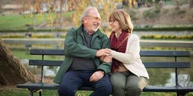 Couple talks on a bench with arms linked
